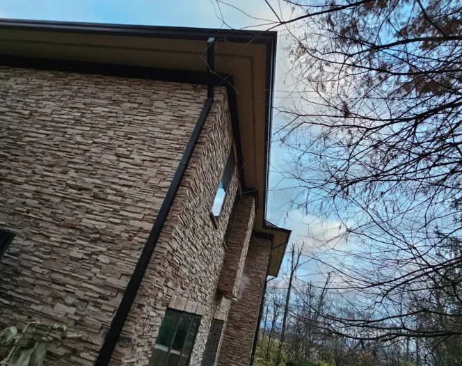 A stone building with dark trim under a cloudy sky